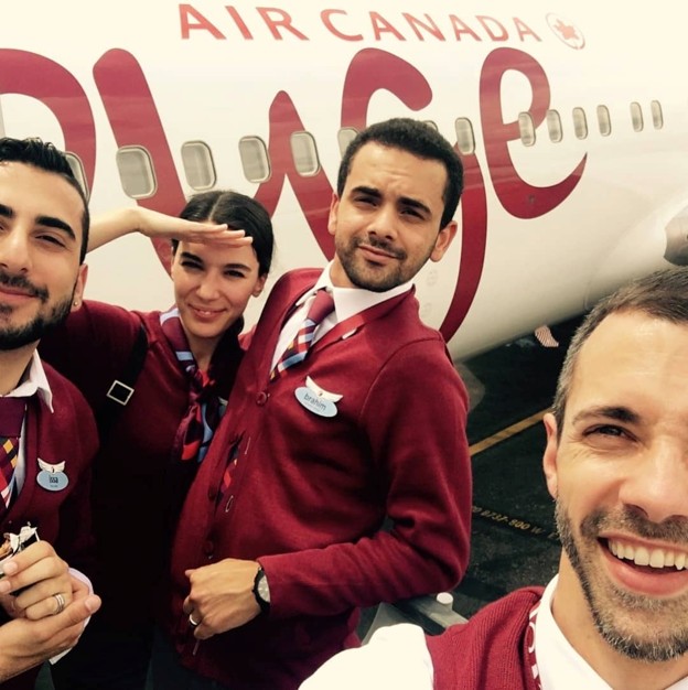 Picture2 - The Canada Times Four airline staff in maroon uniforms pose for a selfie in front of a white Air Canada Rouge aircraft with red branding.