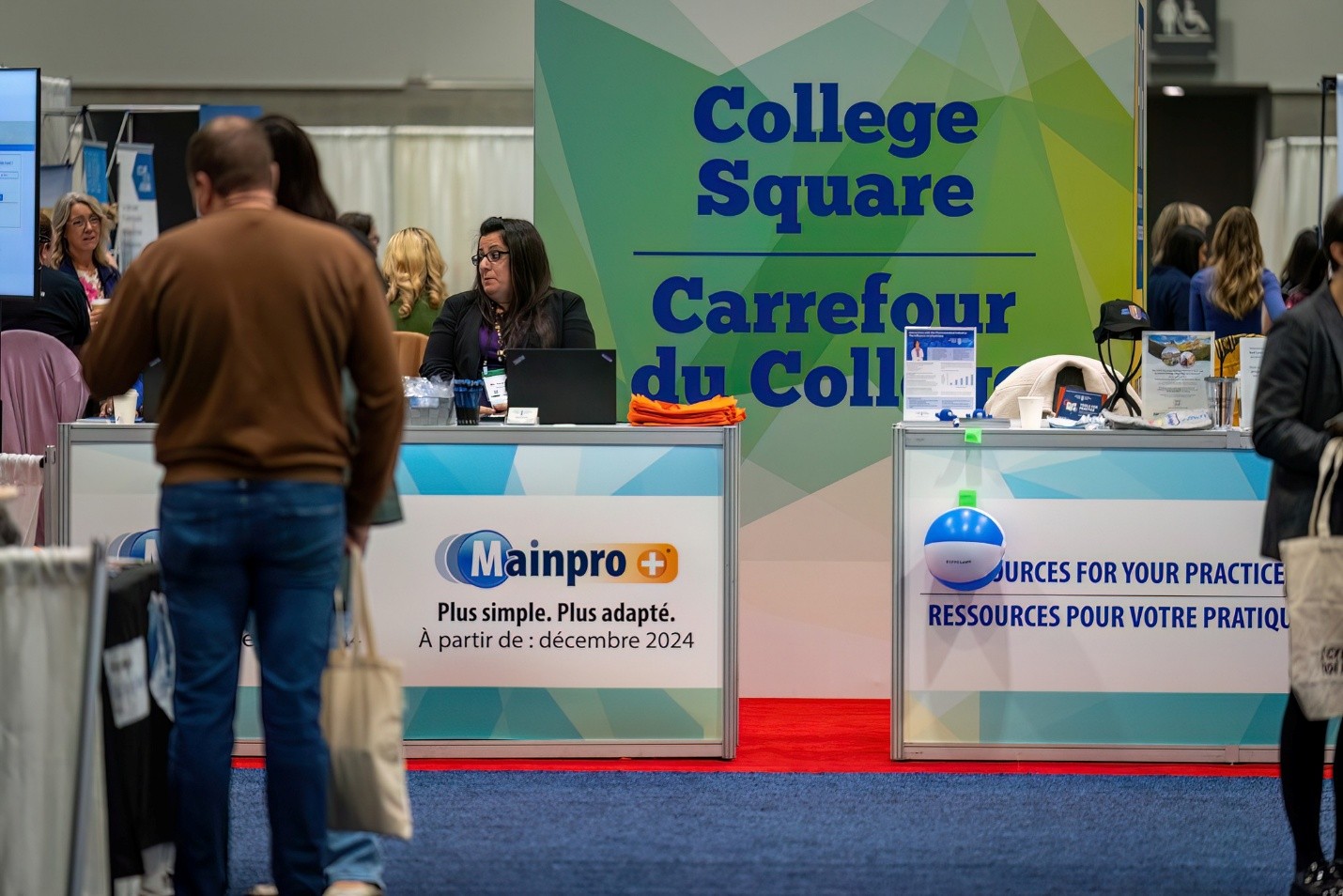 Picture36 - The Canada Times Trade booth at a college fair with a colorful backdrop reading 'College Square / Carrefour du College' and a receptionist at a laptop on the counter.