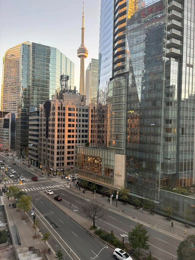 Picture3 - The Canada Times Downtown street with modern glass skyscrapers; the CN Tower rises in the background.