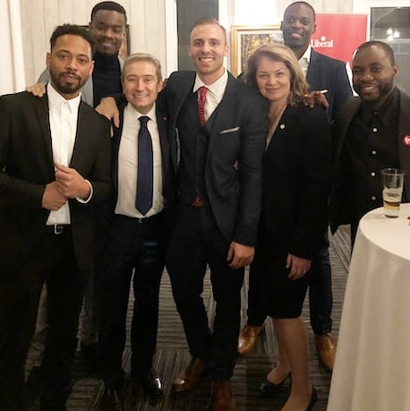 3 - The Canada Times Group of eight professionals in suits posing at a reception, smiling for the camera.