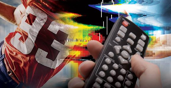 4 - The Canada Times Close-up of a hand holding a remote control, with a football player in a red jersey and colorful motion effects in the background.