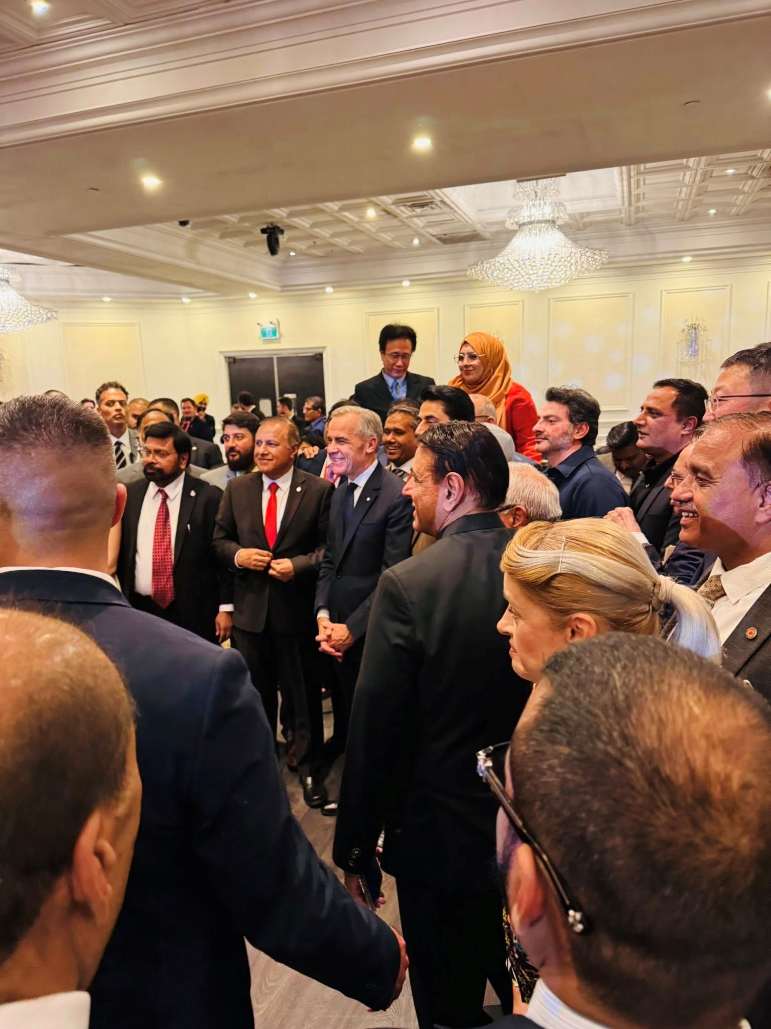 11 - The Canada Times Audience of professionals in a banquet hall; two people shake hands in the foreground as others mingle nearby.
