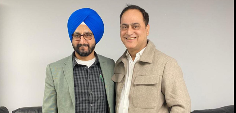 12 - The Canada Times Two men posing together and smiling, one wearing a blue turban and glasses, the other in a beige jacket.