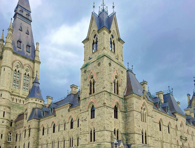 6 - The Canada Times Stone castle-like building with tall towers and pointed arches under a cloudy blue sky.