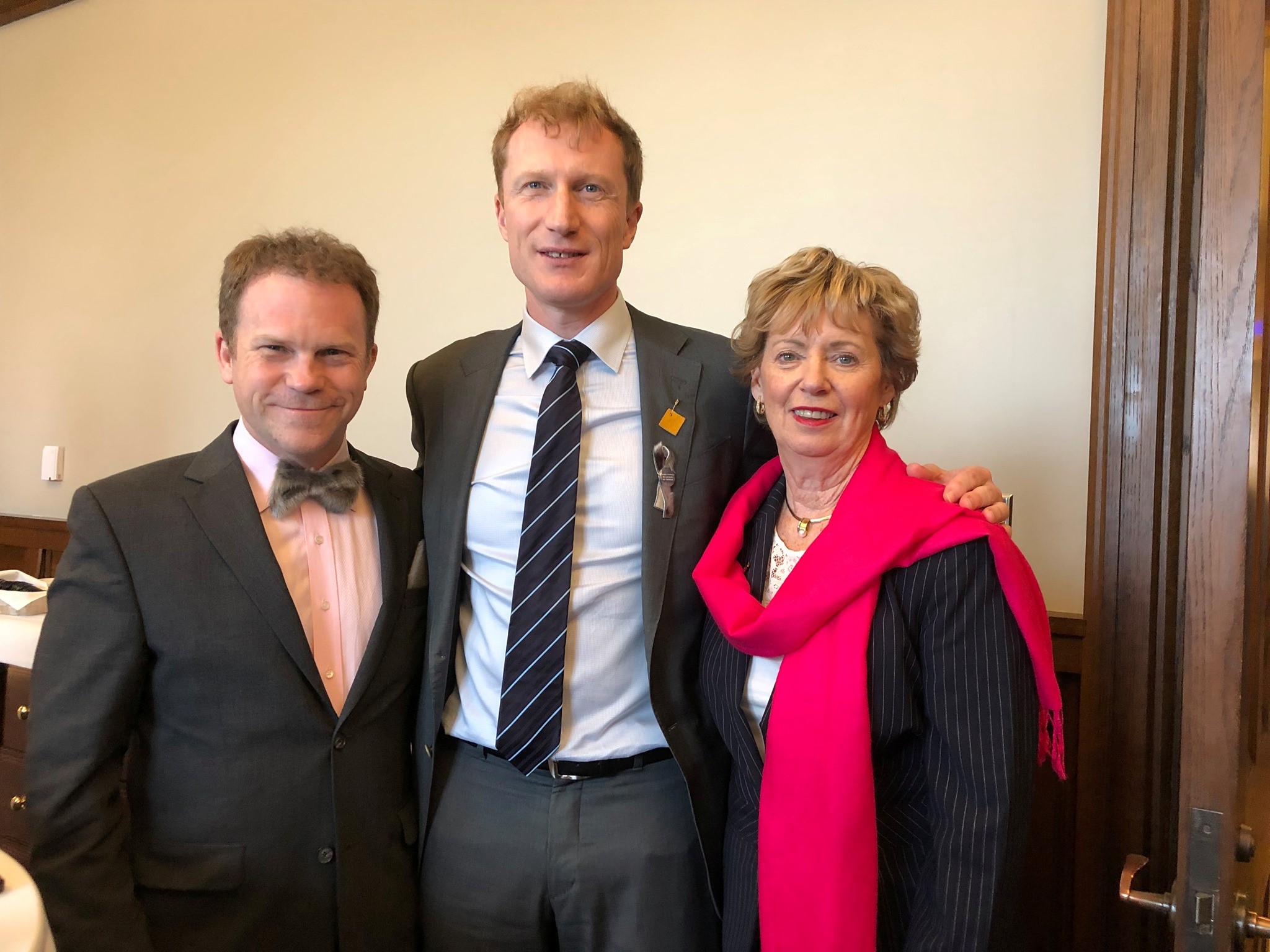 9 - The Canada Times Three adults in formal attire posing together indoors, smiling for the photo.