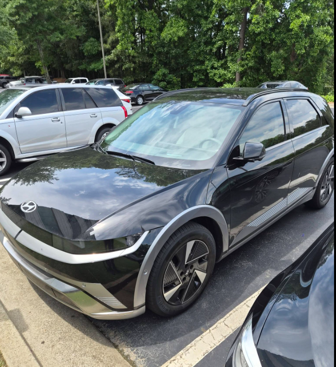 10 - The Canada Times Black Hyundai Ioniq 5 parked in a lot next to other cars with trees in the background on a sunny day