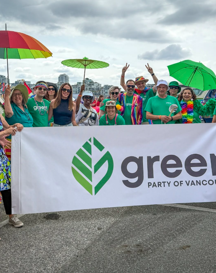 7 - The Canada Times Group of people at a parade holding a banner for the Green Party of Vancouver, with colorful umbrellas and rainbow accessories in the background.