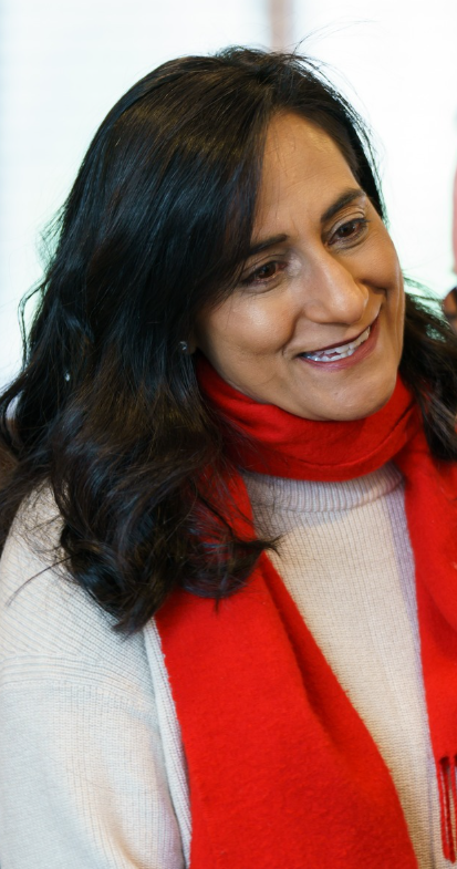 7 - The Canada Times Woman with dark hair wearing a red scarf, smiling warmly.