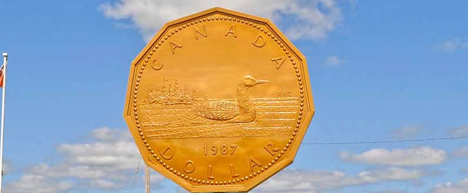 Large golden octagonal coin sculpture showing a canoeist paddling on water, with CANADA DOLLAR 1987 inscribed around the edge.