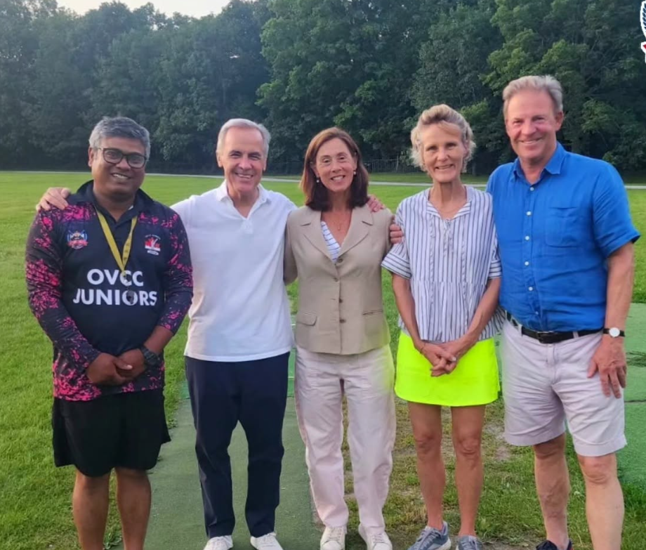 10 - The Canada Times Five adults standing shoulder to shoulder on a grassy field with trees in the background, smiling for the photo.