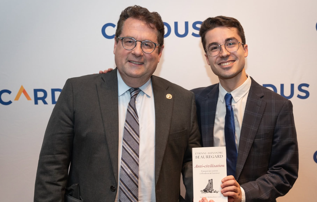 12 - The Canada Times Two men in business suits posing together at an event; the younger man holds a booklet titled 'Anti-civilisation' by Etienne-Alexandre Beauregard.
