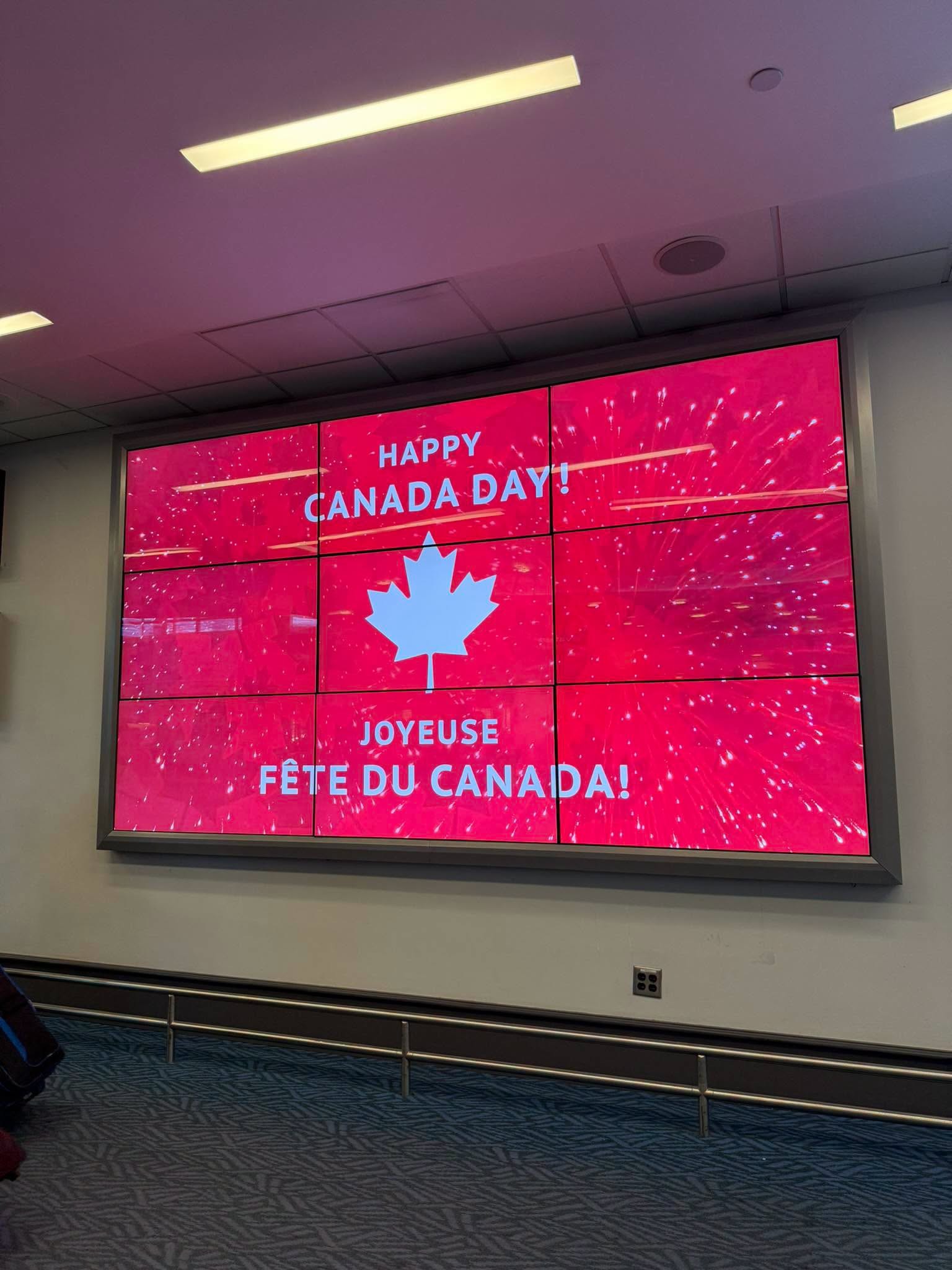 2 - The Canada Times Large red digital screen displaying 'HAPPY CANADA DAY!' with a white maple leaf, in a multi-panel wall.