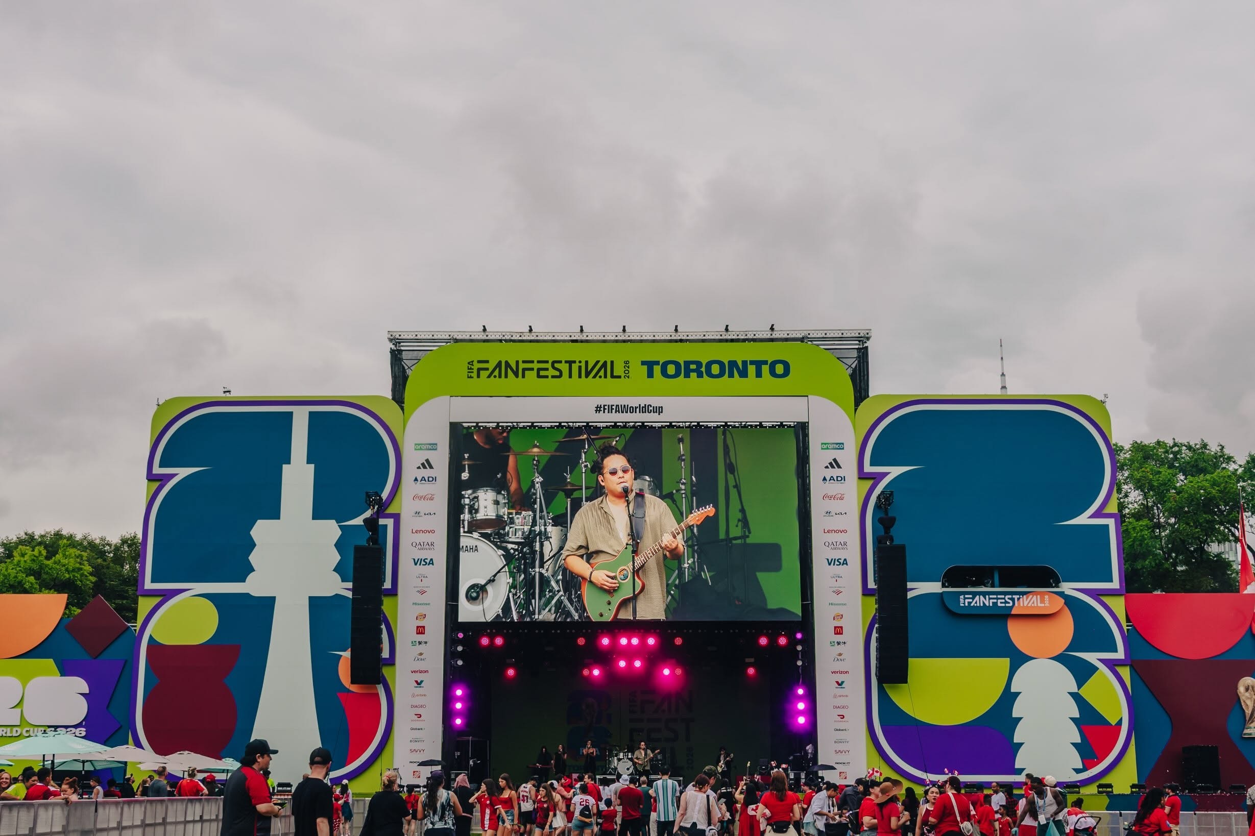 Concert stage at FIFA Fan Festival Toronto with a musician playing guitar on a brightly colored backdrop.